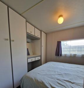 Habitación pequeña con cama y ventana en Stacaravan Verhuur Drenthe, en Eext