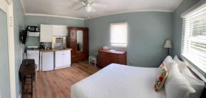 a bedroom with a white bed and a kitchen at Cherokee Lodge in San Diego