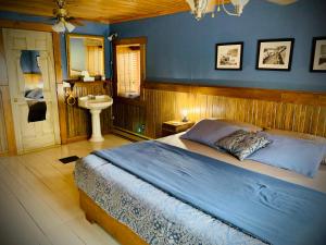 a bedroom with a large bed and a sink at Chalet & Gîte Capitainerie du Passant in Grandes-Piles
