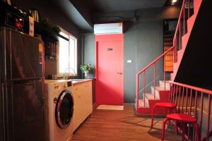 a kitchen with a washing machine and a red door at Kratib House @ MRT Queen Sirikit 400m in Bangkok