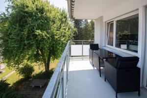 a balcony with a table and chairs and a tree at Moderne & helle Wohnung mit Netflix & Bergsicht in Wetzikon