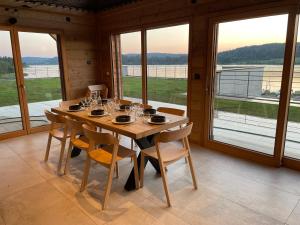 a wooden table with chairs in a room with windows at Chalets Coeur du Lac in Malbuisson