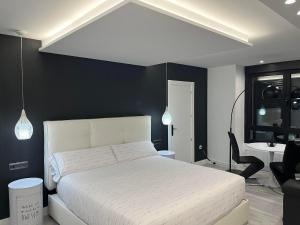 a bedroom with a white bed and a black wall at Black and White Suite Castro Urdiales in Castro-Urdiales