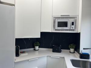 a kitchen with white cabinets and a microwave at Black and White Suite Castro Urdiales in Castro-Urdiales