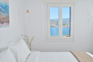 um quarto branco com uma janela com vista para a água em Villa & Studio Hydroussa by Andros Homes em Gavrio