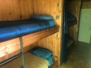 Cette chambre dispose de 3 lits superposés dans un mur en bois. dans l'établissement Hostel Huepil, à Pucón