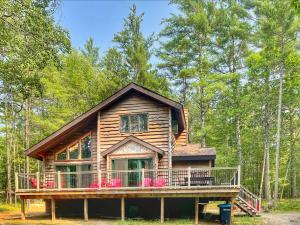 a log cabin in the woods with a large deck at ADK Cabin with Hot Tub, Near Whiteface, Lake Placid, Fire Pit, Game Rm in Jay