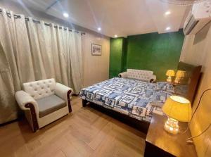 a bedroom with a bed and a chair and a table at Luxury Private Top Floor Apartment in Heart of Bahria Town in Lahore