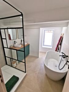 een badkamer met een wit bad en een spiegel bij Charmante maison de village in Caumont-sur-Durance