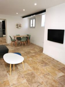 een woonkamer met een tafel en een tv aan de muur bij Charmante maison de village in Caumont-sur-Durance