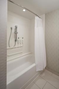 El baño incluye bañera blanca con cortina de ducha. en SpringHill Suites by Marriott Philadelphia Airport / Ridley Park en Ridley Park
