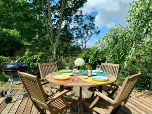 een houten tafel met stoelen en een grill op een terras bij Peaceful Norfolk Broads 1 Bedroom 2 bath annexe in Halvergate