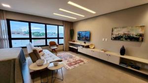 sala de estar con sofá blanco y ventana grande en Loft Ultra Luxo há Poucos Passos do Shopping CG. en Campo Grande