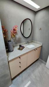 a bathroom with a sink and a mirror at Loft Ultra Luxo há Poucos Passos do Shopping CG. in Campo Grande