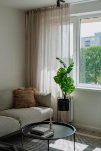 ein Wohnzimmer mit einem Sofa und einem Tisch mit einer Pflanze in der Unterkunft BALI apartment in central Mažeikiai SELF CHECK-IN 24H in Mažeikiai