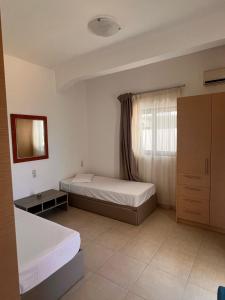 a bedroom with two beds and a window at Panorama Village Hotel in Agia Pelagia