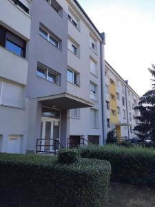 a white apartment building with bushes in front of it at Apartman Ines in Velika Gorica