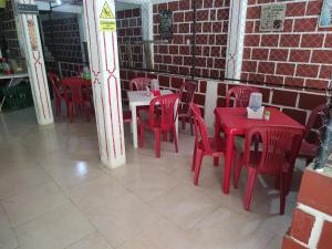 Habitación con mesas y sillas rojas y pared de ladrillo. en Casa hospedaje mayesty, en San Cipriano