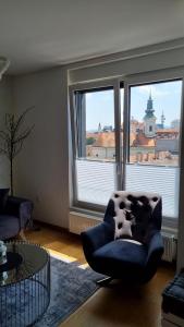 a living room with a chair and a large window at Centar view lux in Novi Sad