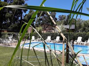 a pool with white chairs and a house at Complejo de Cabañas Villapaz in Mar del Plata