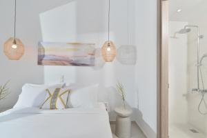 um quarto branco com uma cama e luzes pendentes em Villa & Studio Hydroussa by Andros Homes em Gavrio