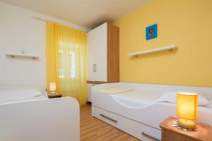a bedroom with two white beds and a yellow wall at House Gita in Sutivan