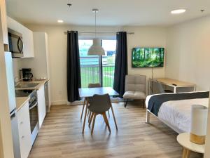 a bedroom with a bed and a table and a kitchen at APPART-HOTEL L'UNI in Quebec City