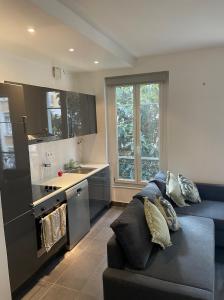 Il comprend un salon avec un canapé bleu et une cuisine. dans l'établissement Appartement moderne bien situé, à Levallois-Perret
