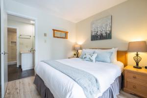 a bedroom with a large white bed and a bathroom at Wildwood Lodge by Outpost Whistler in Whistler