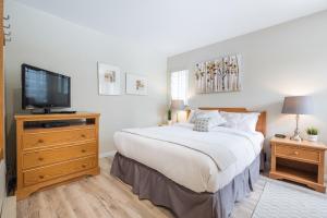 Dormitorio con cama y tocador con TV en Wildwood Lodge by Outpost Whistler, en Whistler