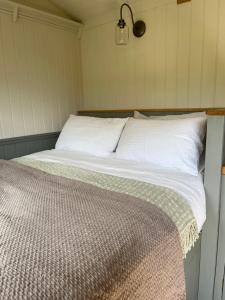 Bett mit weißer Bettwäsche und Kissen in einem Zimmer in der Unterkunft Troytown Farm Shepherds hut in Puddletown