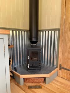 una estufa dentro de una habitación en una casa en Troytown Farm Shepherds hut en Puddletown
