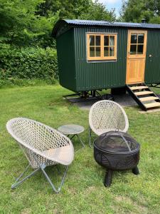 a backyard with two chairs and a grill and a house at Troytown Farm Shepherds hut in Puddletown +3 photos