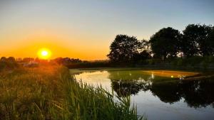 a sunset on a golf course with a pond at Luxury Farm Breaks in Wisbech