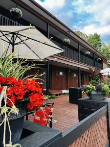 un patio con flores rojas y una sombrilla en Hotel Le Petit Lac Sainte-Adèle en Sainte-Adèle
