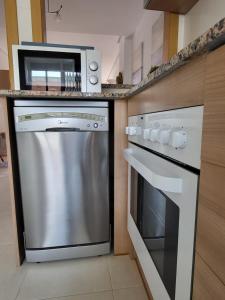 a kitchen with a stainless steel dishwasher and a microwave at La Casa de la Rivera in Culla