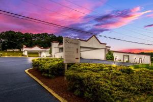 una señal frente a una casa con una puesta de sol en Red Roof Inn New Stanton, en New Stanton