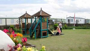 a childrens play set in a yard with a playground at Jolly Jacks Static Sanctuary in Heysham