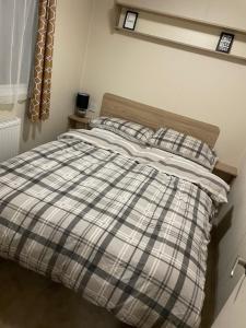 a bed with a plaid blanket and pillows at Jolly Jacks Static Sanctuary in Heysham