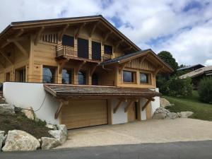 a log home with a balcony and a garage at Chalet du Feug in Combloux