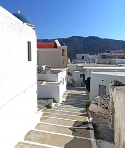 un callejón con edificios blancos y montañas al fondo en Στου Βάρδα, Χώρα, Σέριφος, en Serifos Chora