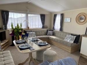 a living room with a couch and a table at Comfy Cosy Caravan_Romney Sands in Littlestone-on-Sea