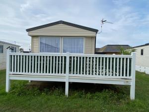 a white wooden bench in front of a house at Comfy Cosy Caravan_Romney Sands in Littlestone-on-Sea