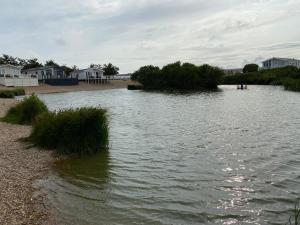 a large body of water with houses and grass at Comfy Cosy Caravan_Romney Sands in Littlestone-on-Sea