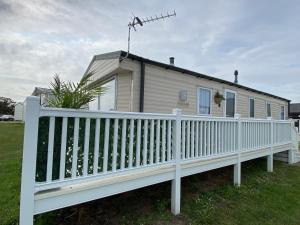 a white fence in front of a house at Comfy Cosy Caravan_Romney Sands in Littlestone-on-Sea