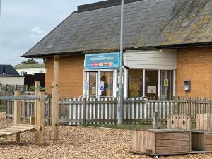 a building with a fence in front of a store at Comfy Cosy Caravan_Romney Sands in Littlestone-on-Sea