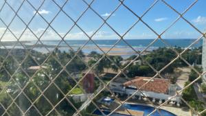 una vista de una ciudad desde detrás de una valla de alambre en Apt agradabilíssimo vista mar, en Lauro de Freitas