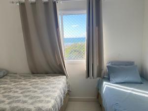 1 dormitorio con cama y ventana en Apt agradabilíssimo vista mar, en Lauro de Freitas