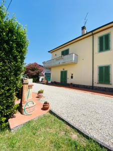 una casa con puertas verdes y una entrada de grava en La Casina di Nonno Enzo, en Vinci