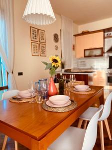 a wooden table with plates and glasses and a vase with a flower at La Casina di Nonno Enzo in Vinci